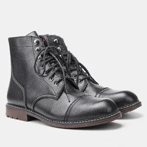 Vista detallada de botas de trabajo de cuero granulado negro con costuras blancas.
