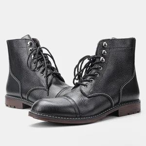 Detalle en primer plano de botas de trabajo en cuero negro granulado con ojales metálicos