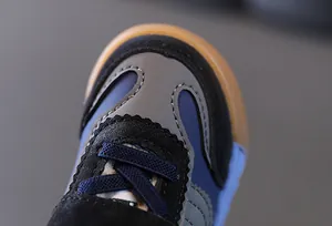 Gros plan de baskets pour enfants bleu marine et gris montrant les coutures et la semelle.