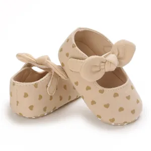 Close-up of soft cotton baby walker shoes with heart prints and decorative bows.