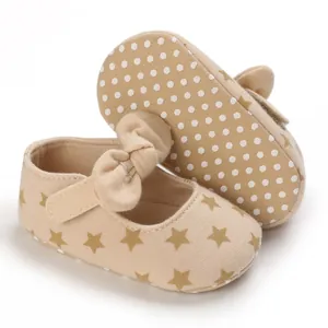Close-up detail of beige cotton baby walker shoes with star prints and a cute bow