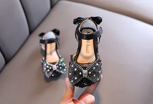 Macro detail view of elegant black girls princess sandals with a sparkling rhinestone bow