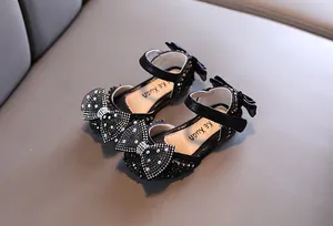 Close-up of black girls' princess sandals featuring large sparkling rhinestone bow details.