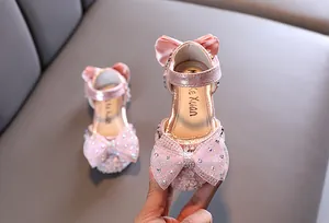 Detail of sparkly pink girl's princess sandals featuring a large rhinestone bow