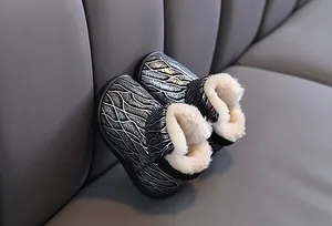 Close-up detail of children's sparkly black snow boots with thick white faux fur lining