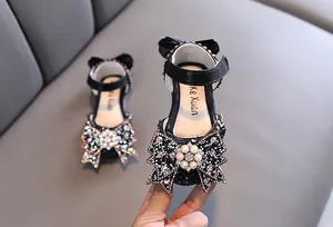 Detail view of black girls' princess shoes with rhinestone-studded bow and pearls