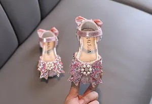 Elegant pink rhinestone princess shoes for girls featuring a large bow and pearl detail