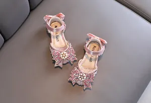 Detail view of sparkling pink girls' princess sandals with rhinestone bowknot and pearls.