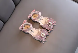 Detailed view of pink glittery girls princess sandals featuring bow and pearl accents