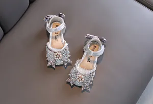Close-up of sparkly silver girls' princess sandals with rhinestone bow detail.