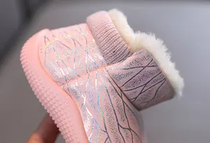 Close-up of pink glittery children's winter boots with warm faux fur lining details.