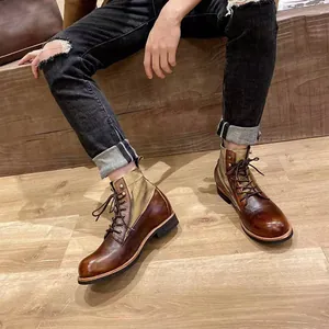 Vista detallada de botas de moto de cuero marrón retro para hombres sobre fondo de madera