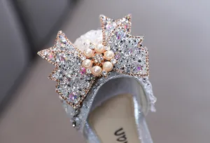 Macro detail of the sparkling rhinestone bow with pearl accent on girl's princess shoe