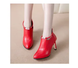 Primer plano de elegantes botines rojos de punta con tacón alto y detalle de cuentas.