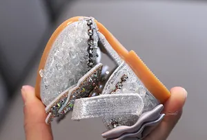 Close-up of flexible soft sole and rhinestone details on girls' silver princess sandals