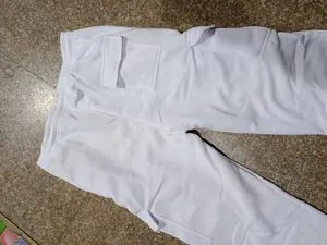 Detailed view of white men's loose cargo pants showing side flap pockets and fabric texture