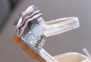 Macro view showing the sparkly silver material, rhinestone details, and satin bow of a girls shoe