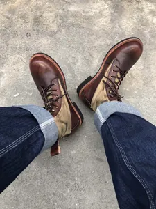 Detalle de botas de moto vintage en cuero marrón y lona usadas con vaqueros azules oscuros