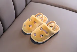 Détail de chaussons en peluche jaune pour bébé avec broderie pêche et bride
