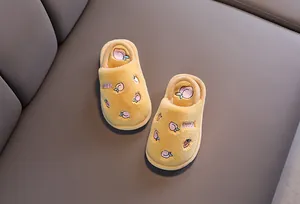 Vue détaillée de chaussons en peluche jaune pour enfants avec broderie pêche rose.