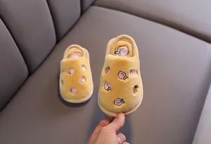 Vue détaillée des pantoufles en peluche jaune pour tout-petits avec broderie de pêche.