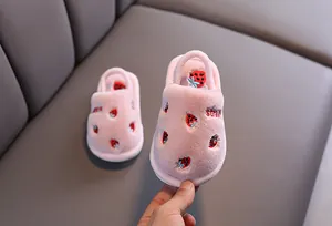 Gros plan de jolis chaussons en peluche rose pour enfants avec des motifs fraises