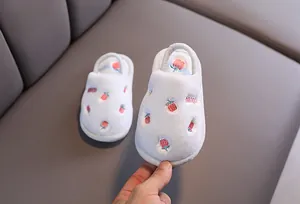 Gros plan d'un chausson en peluche blanc pour enfant avec broderie fraise.