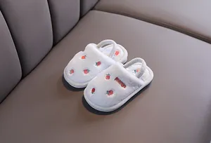 Vue détaillée des chaussons en peluche bleus avec broderie fraise pour enfants