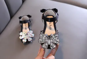 Close-up of girls' black sandals with sparkling rhinestone butterfly ornament
