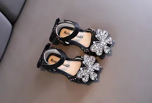 Close-up of sparkling rhinestone butterfly and bow detail on elegant black girls sandals