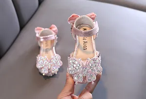 Macro detail of pink girls' princess sandals with sparkling crystal butterfly decoration