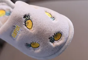 Gros plan sur les chaussons en peluche pour enfants avec broderie carotte jaune