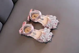 Detail shot of sparkling pink girls' princess sandals with rhinestone butterfly.
