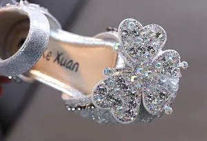 Macro detail of a sparkling rhinestone butterfly on a silver girl's princess shoe.