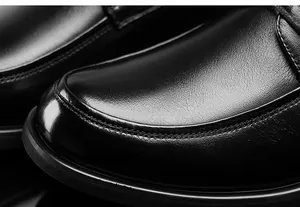 Macro close-up detail of premium black cowhide leather on a men's business dress shoe