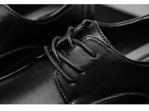 Close-up detail of black genuine leather business dress shoe showing fine grain and lacing