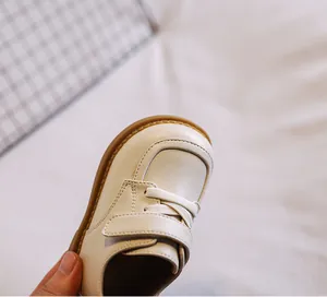 Close-up detail of cream baby girl leather shoes with soft sole and velcro strap
