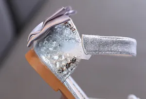 Detailed macro view showing the rhinestone and satin bow on silver glitter princess sandal