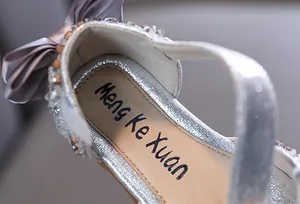 Macro detail of girl's silver princess sandal with rhinestone and purple bow decoration