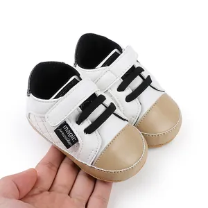 Detailed view of white baby prewalker shoes with tan toe cap and black velcro straps.