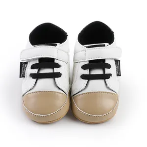 Close-up of white and tan soft-sole baby pre-walker shoes with velcro strap