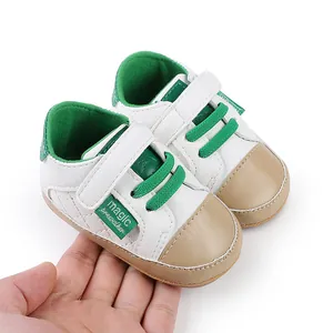 Detailed view of white and green baby walking shoes held in a hand for size comparison