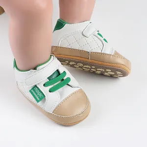 Detail of white and tan baby pre-walker shoes with green accents and velcro strap
