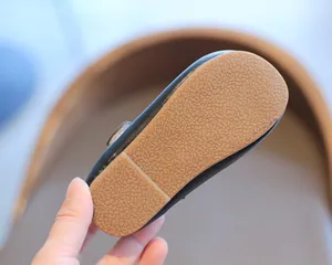 Detailansicht der rutschfesten braunen Gummisohle eines schwarzen Loafers für Kleinkinder