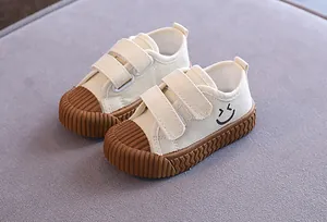 Detailansicht weißer Kinder-Stoffschuhe mit strukturierter brauner Keks-Gummisohle.
