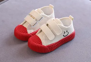Kinder-Segeltuchschuhe in Weiß mit roter geriffelter Sohle und gesticktem Smiley-Detail