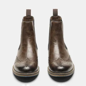 Front view detail of brown retro men's Chelsea boots with elegant brogue carving.