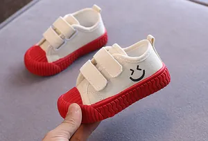 Nahaufnahme von Baby-Leinwandschuhen mit roten weichen Sohlen und Smiley-Muster