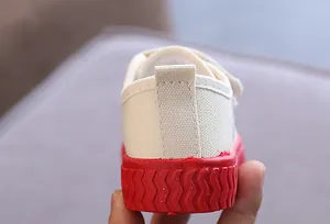 Rückansicht von Kinder-Stoffschuhen in Weiß mit roter gewellter Gummisohle