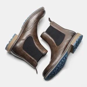 Detail of men's vintage brown Chelsea boots with brogue carving and blue lug soles.